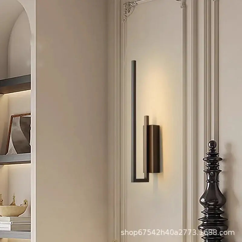 Modern gold brass wall light sconce with frosted glass and sleek black metal frame providing warm ambient lighting