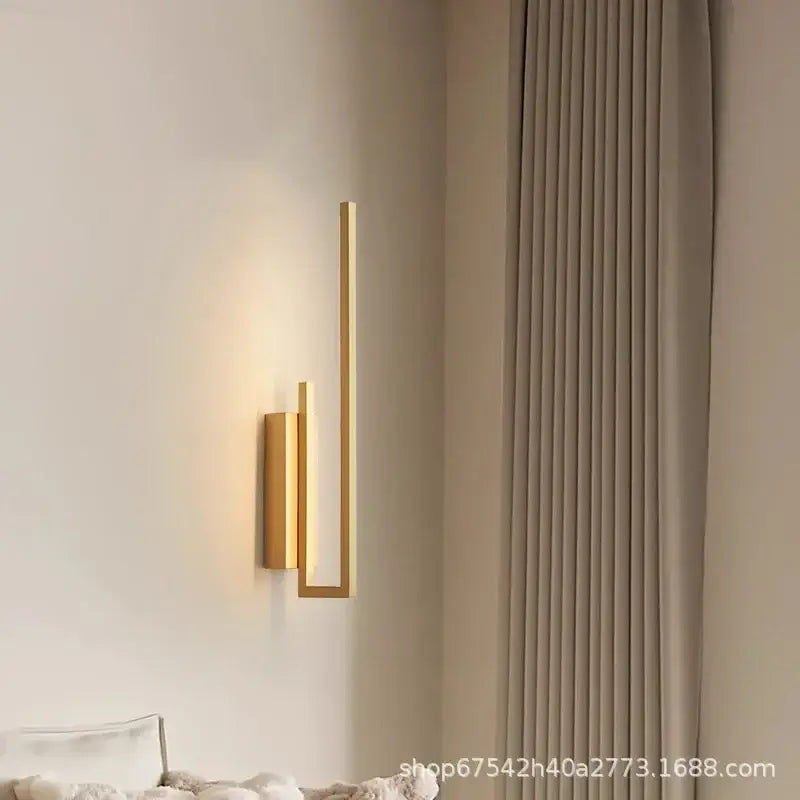 Modern gold brass wall light sconce with a minimalist angular design and frosted glass for bedroom use