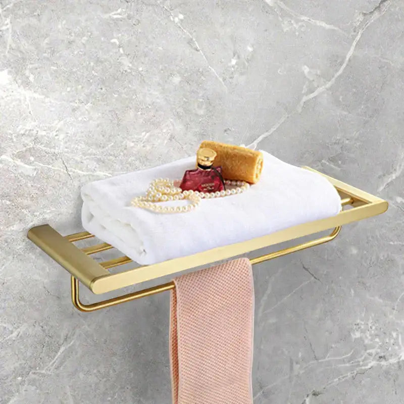 Modern gold brushed bathroom accessories set featuring a gold-toned metal towel rack holding white and pink towels decorbites bathroom
