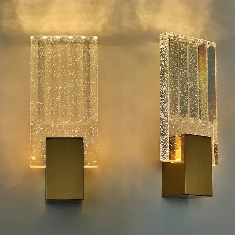 Modern gold bubble crystal led wall sconces with rectangular golden bases and speckled glass panels emitting warm glow