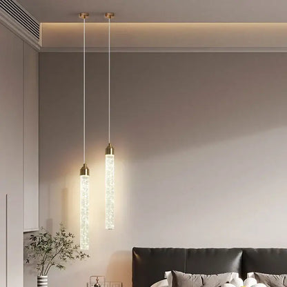 Two elegant gold bubble crystal pendant lights with translucent cylindrical bodies emit a warm glow for dining rooms