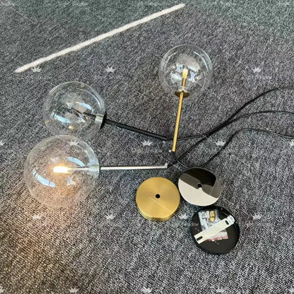 Modern gold bubble glass ball pendant light with brass and black metal accents featuring clear glass globe bulbs