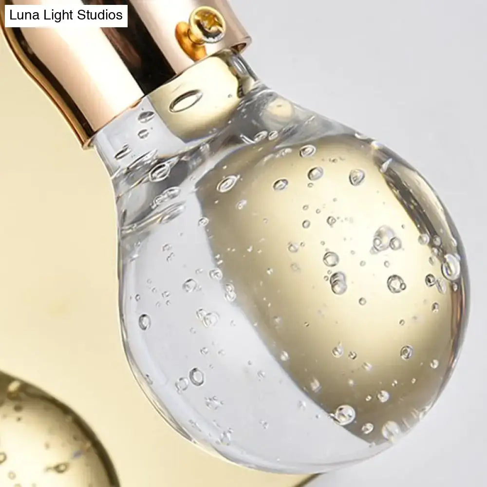 A clear bulb shaped crystal wall sconce with gold metallic cap and bubbles for 110v-120v bedroom lighting