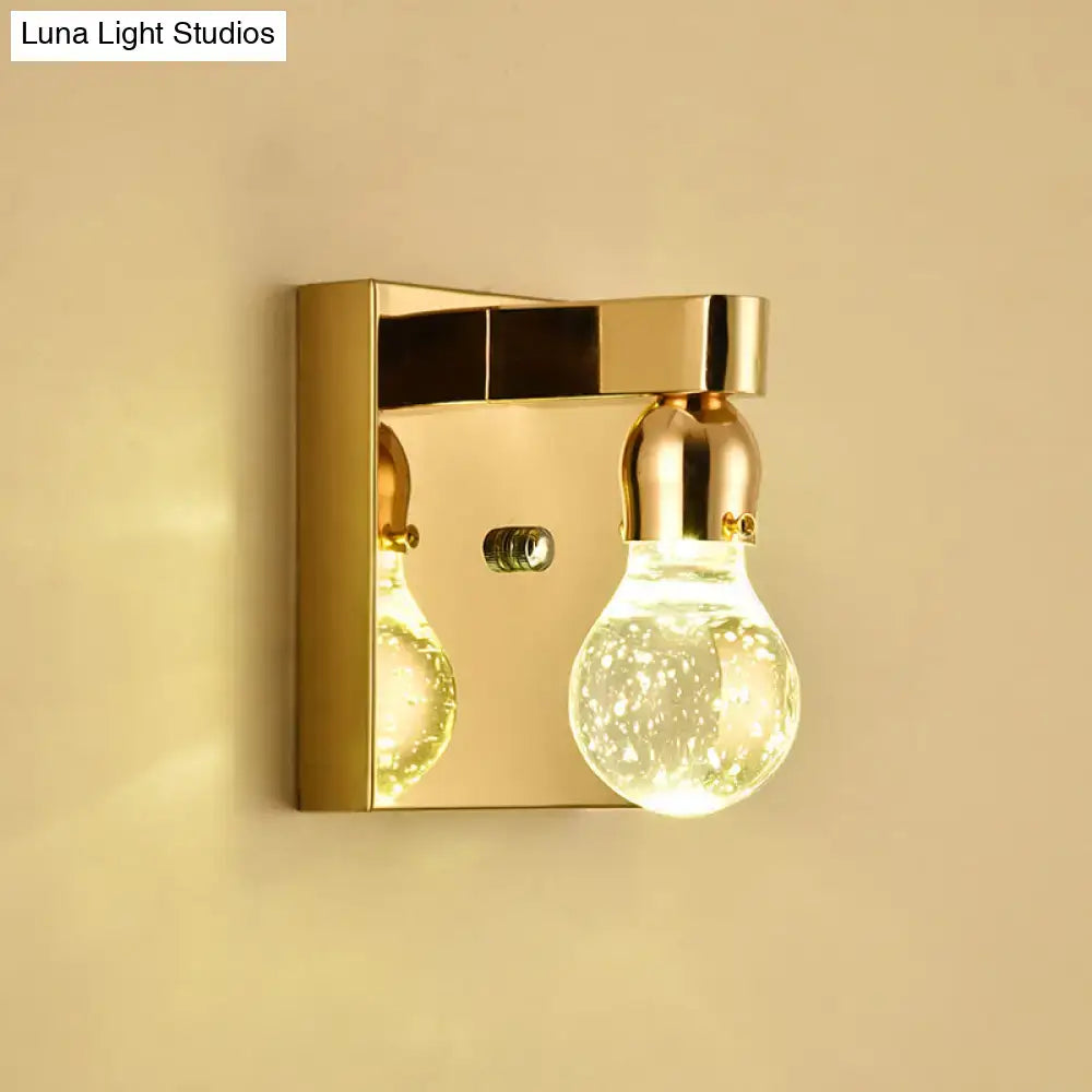 Gold-finished modern wall sconce with two illuminated textured glass bulb shaped fixtures for 110v-120v use