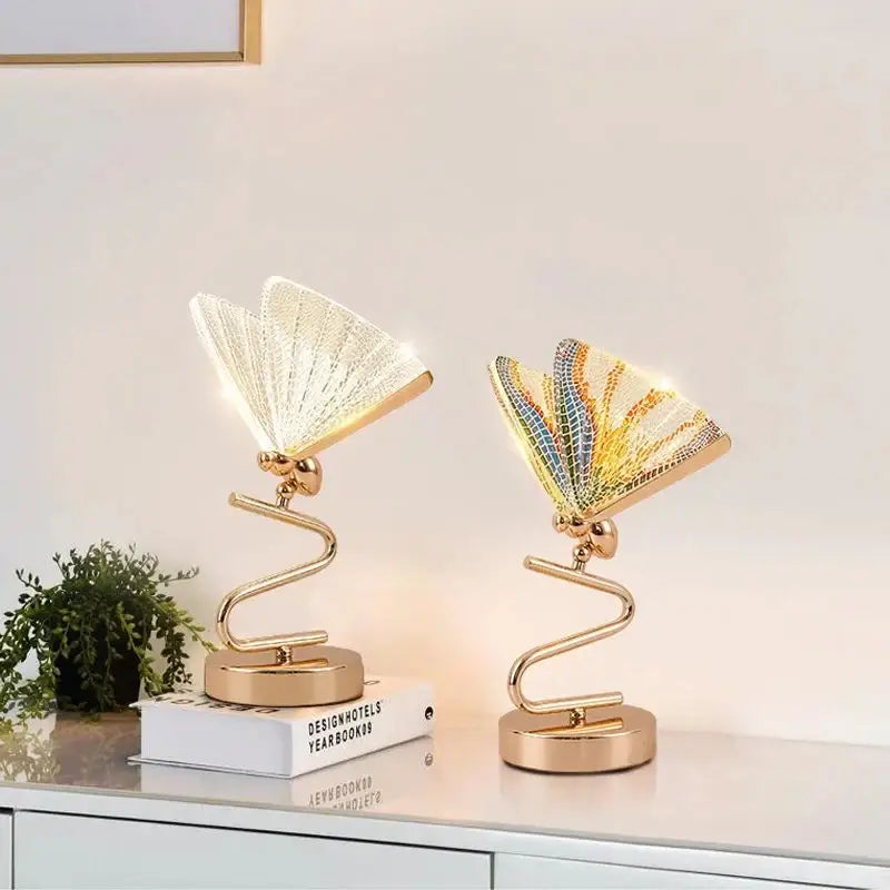 Two modern gold butterfly led pendant lamps with illuminated fan-like wings in white clear and rainbow mosaic colors