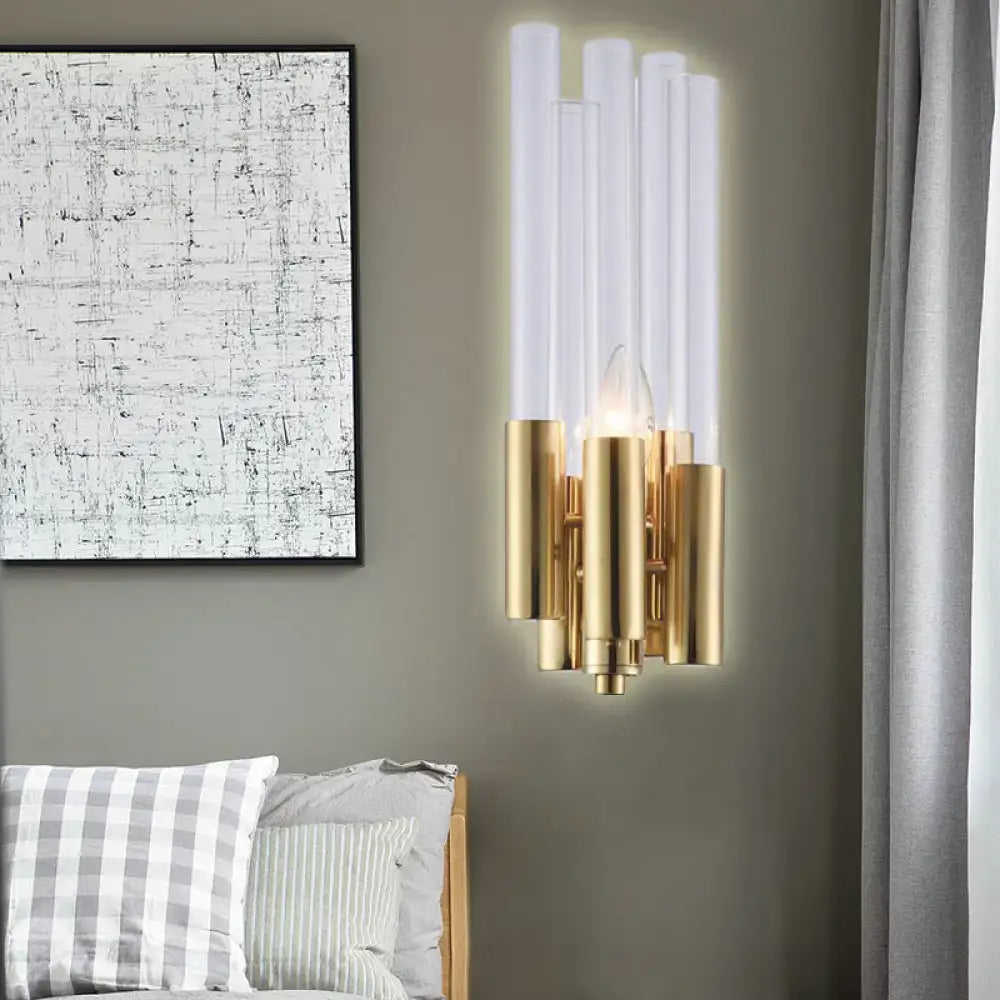 Modern gold candelabra sconce with flute crystal shade and translucent glass tubes emitting warm bedroom light