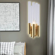 Modern gold candelabra sconce with flute crystal shade and translucent glass tubes emitting warm bedroom light