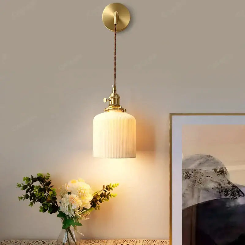Modern gold ceramic wall lamp with a warm-toned brass pendant, ribbed off-white glass shade, and twisted brown cord for decorbites ceramic wall decor