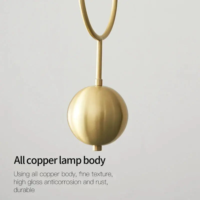 A sleek spherical brass pendant lamp with polished copper finish as a modern chandelier light fixture for living room