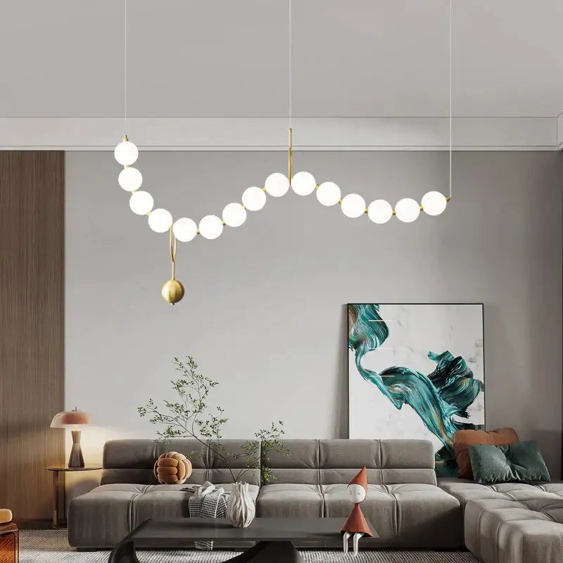 Modern gold-toned chandelier light fixture with spherical white glass bulbs in an elegant curved design for living room