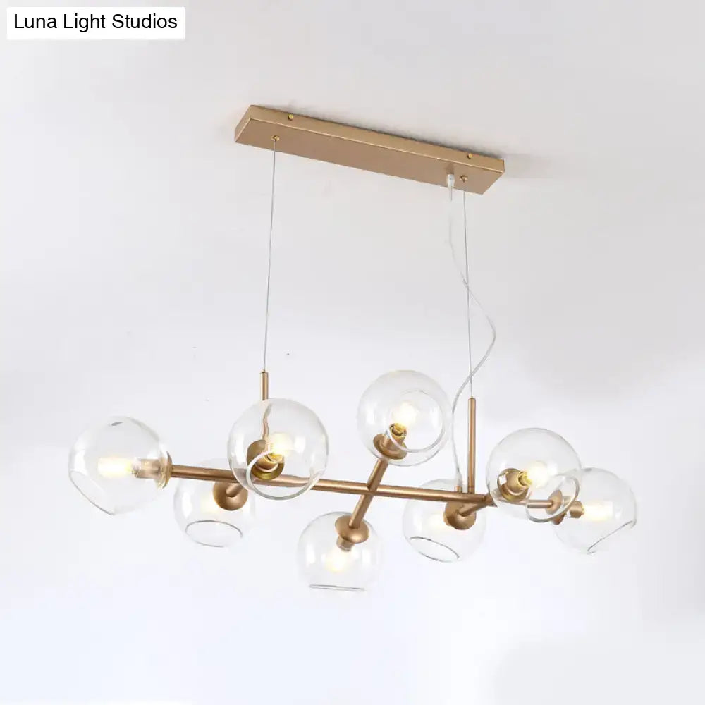Modern gold chandelier with brass finish and clear glass globe shades for elegant dining room lighting