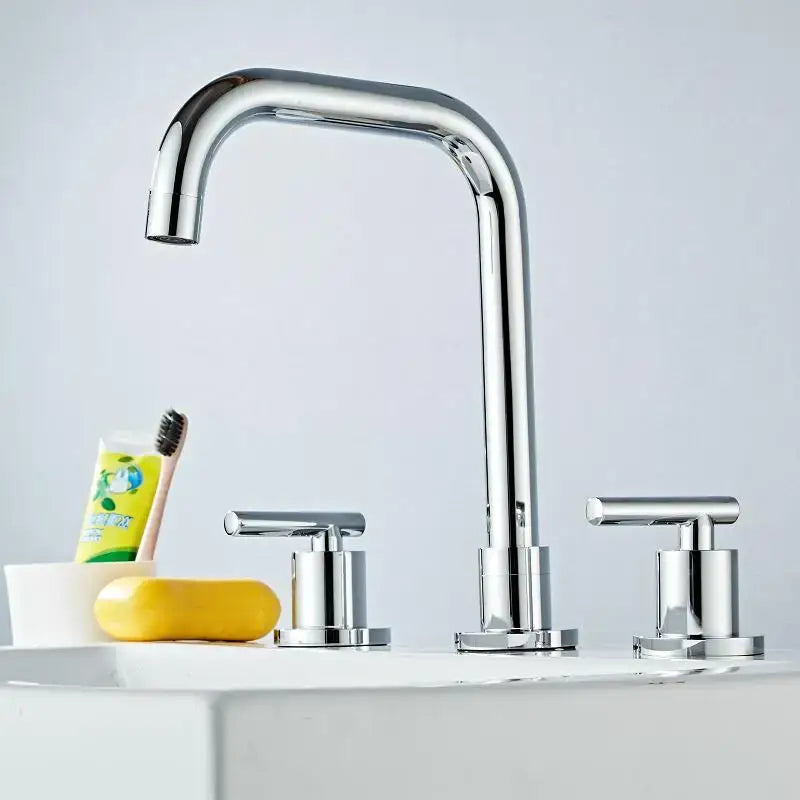 Modern gold and chrome brass basin faucet with sleek curved spout and two cylindrical handles for kitchen sink tap
