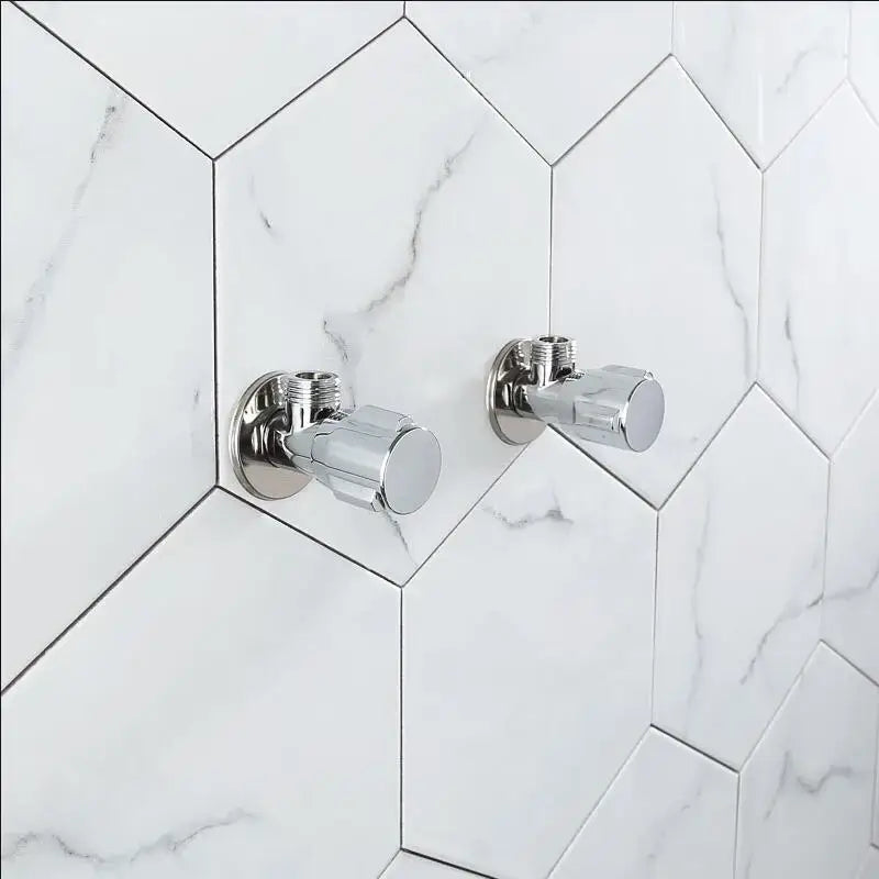 Two sleek chrome brass triangle valve bathroom faucets mounted on white marble hexagonal tiles by decorbites brass