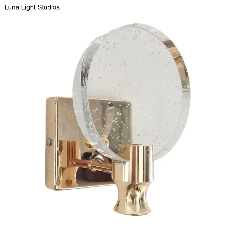 A modern gold circle panel wall light with a direct wired electric metal base and clear bubble crystal glass shade