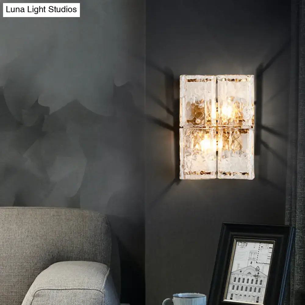 Modern gold wall sconce with four clear water glass textured panels arranged in a square grid for bedroom use
