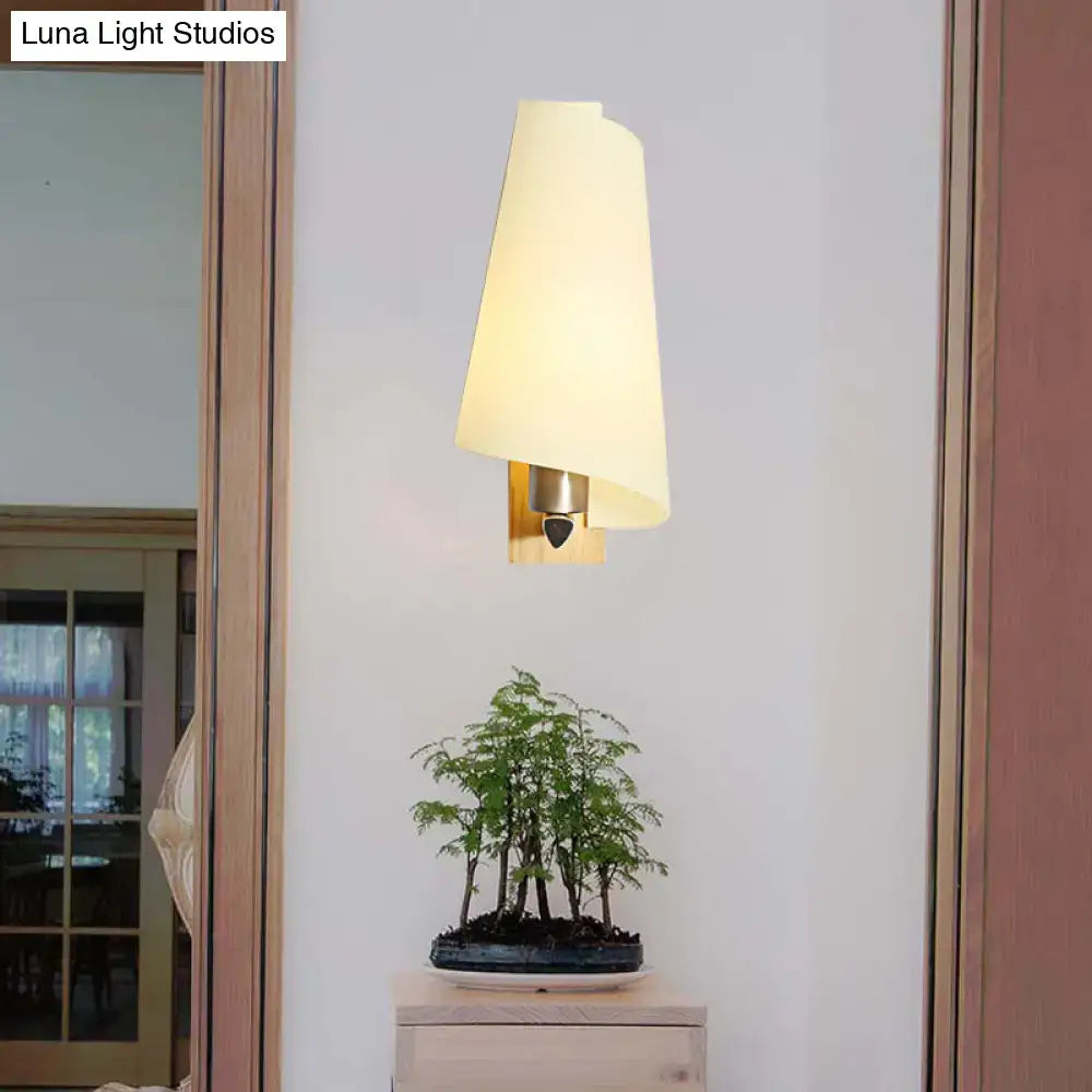 Modern cream-colored sconce light with a gold coolie shade and milk glass featuring brushed brass hardware for bedroom use