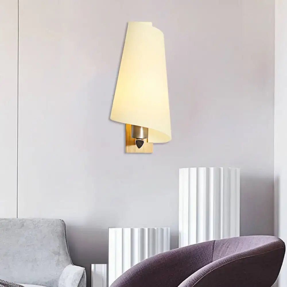 Modern gold-toned coolie shade sconce light with cream fabric shade and milk glass detail for bedroom use