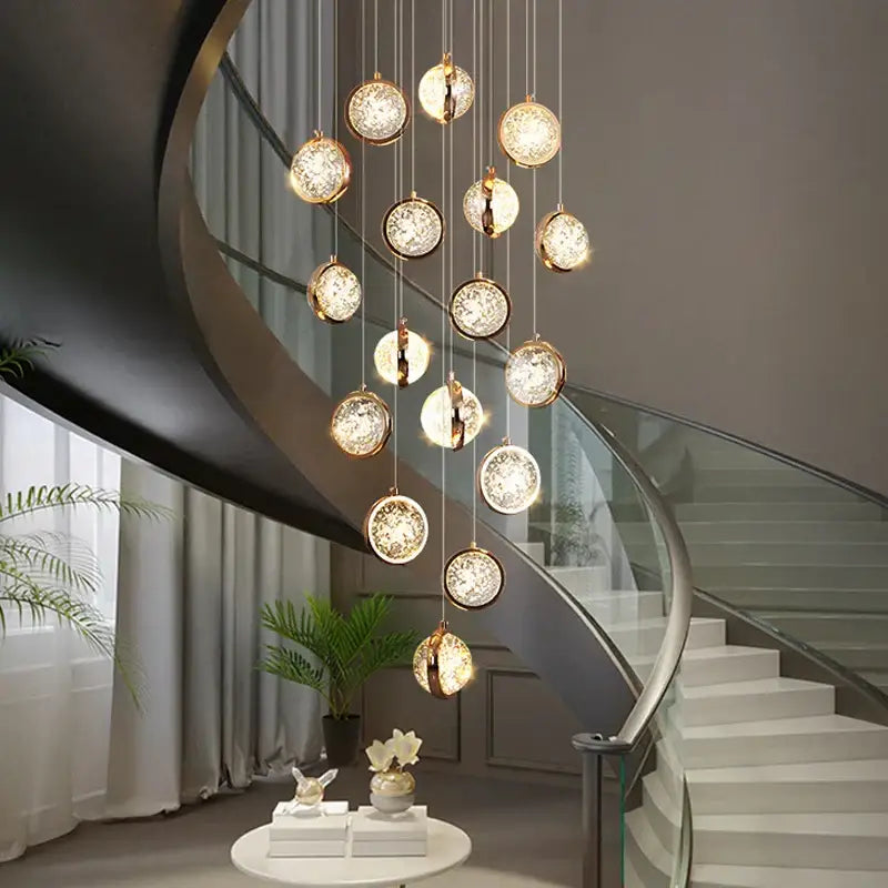 Modern gold crystal ball chandelier with crystal accents hanging above a staircase as a ball chandelier lighting