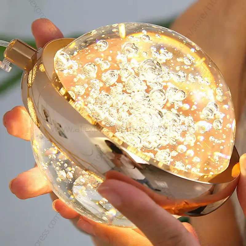 Modern gold crystal ball chandelier with a spherical glass dome filled with glowing translucent bubbles and warm light