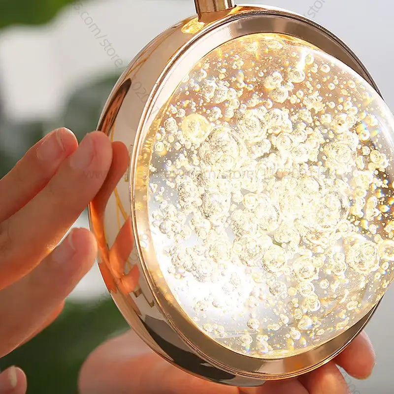 Modern gold crystal ball chandelier with a round glass ball filled with bubbles glowing warmly for staircase lighting