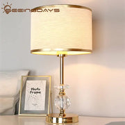 Modern gold crystal ball table lamp with off-white fabric shade and crystal embellishments for bedroom use