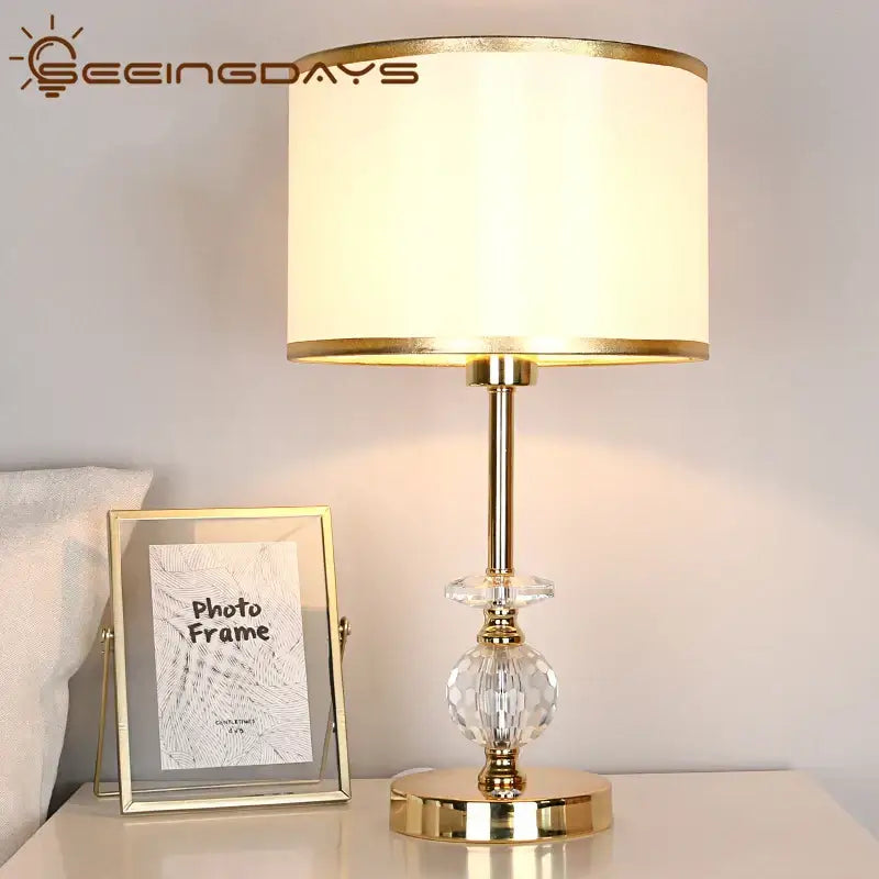 Modern gold crystal ball table lamp with cream fabric shade and crystal accents for bedroom lighting