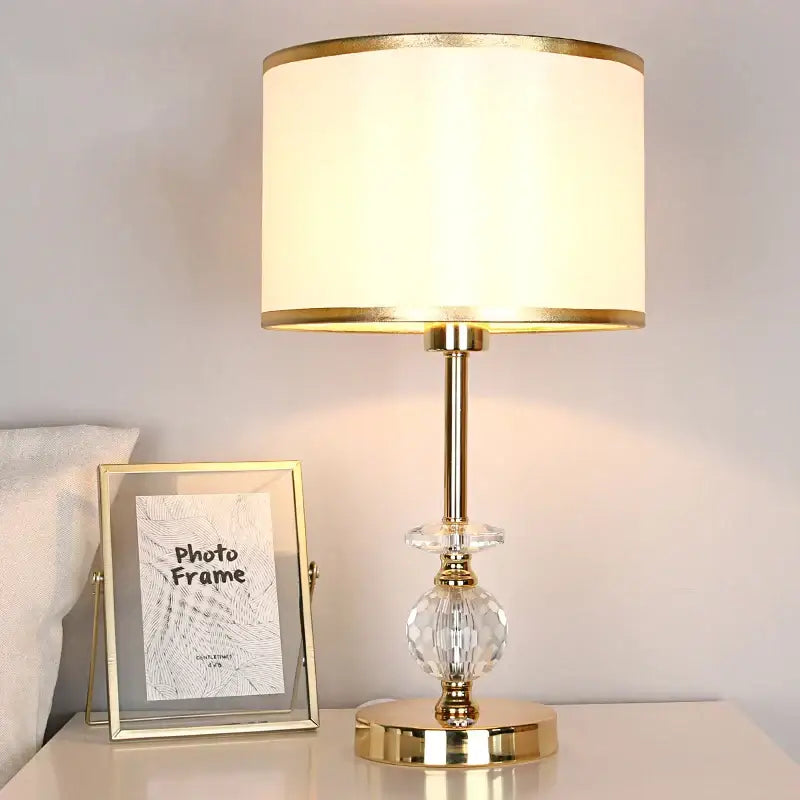 Modern gold crystal ball table lamp with a cream fabric shade and faceted crystal accent for bedroom use