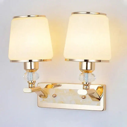 Modern gold crystal bedside wall sconce with two cream fabric shades and bead accents for bedroom lighting