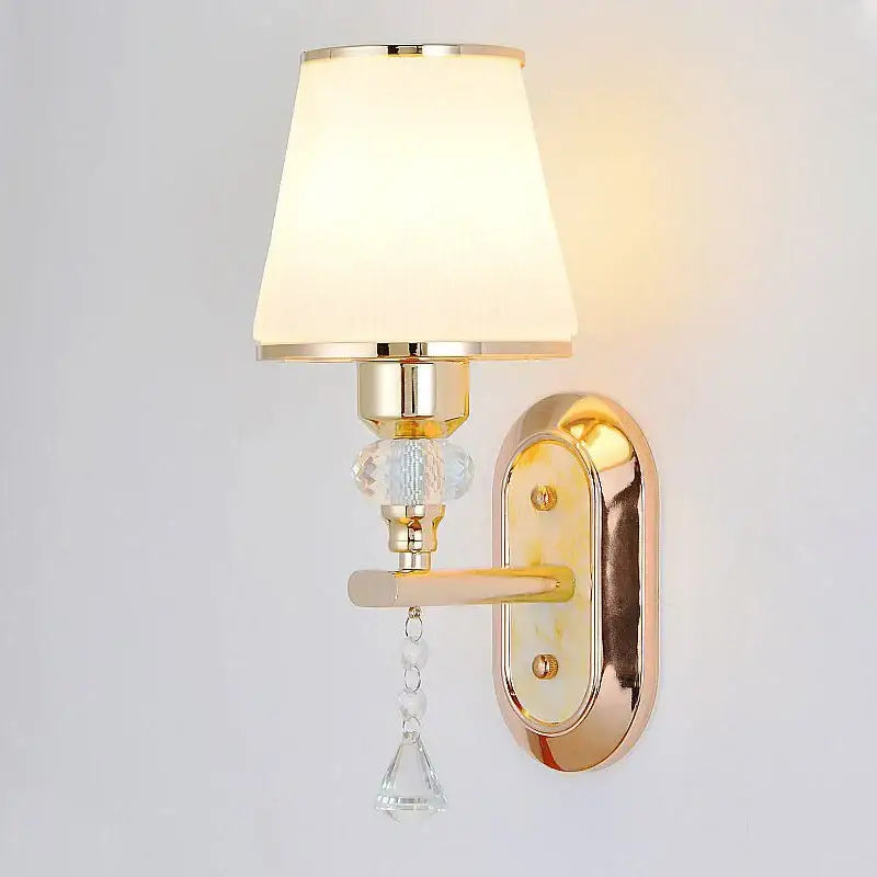 Modern gold crystal bedside wall sconce with cream fabric shade and clear glass bead accents for bedroom lighting