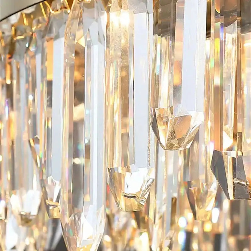Modern gold crystal circle ceiling chandelier with cascading clear crystal prisms creating warm golden decorbites glow