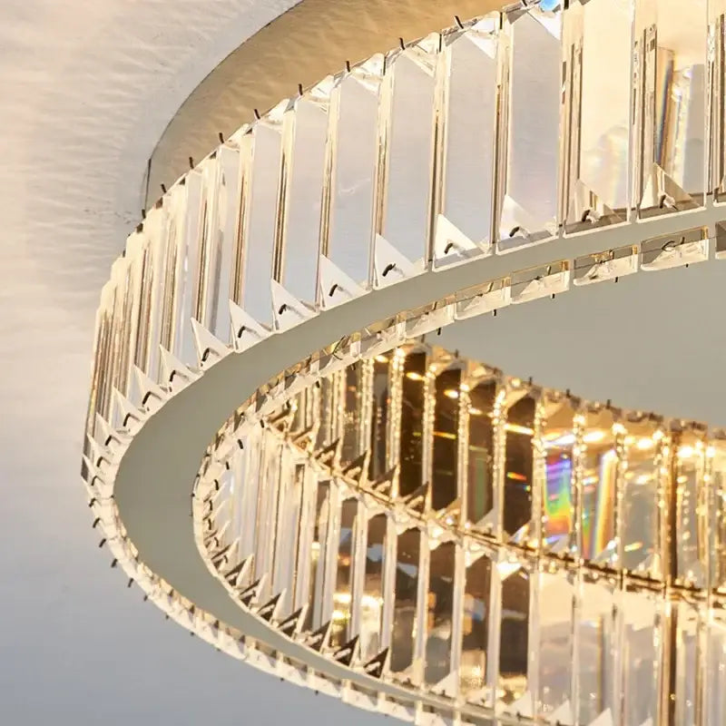 A modern gold crystal circle chandelier with clear crystal prisms in a sleek two-tiered frame for living room decor