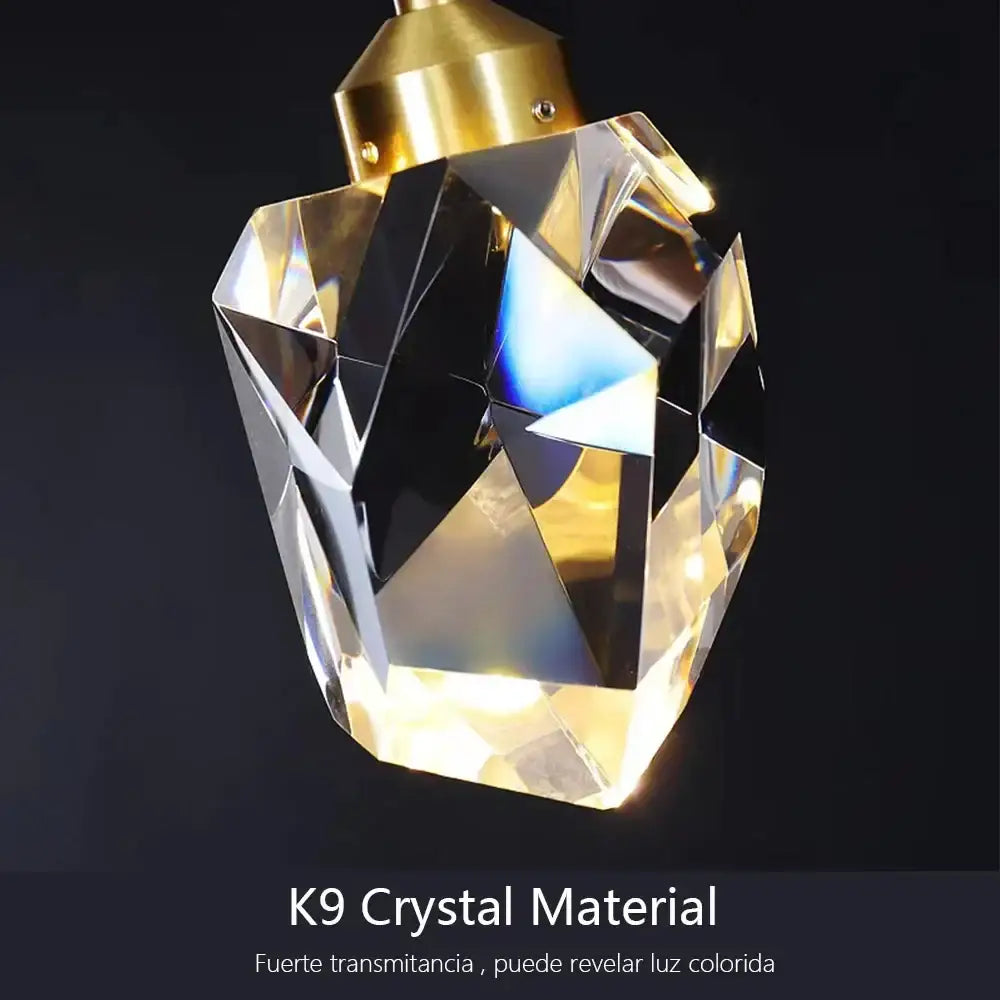 A faceted golden-toned decorbites k9 crystal pendant with a polished brass top for modern crystal dining chandeliers