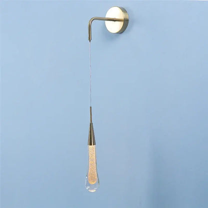 A modern brass-finished wall lamp with a decorbites crystal droplet filled with golden glitter for living room decor