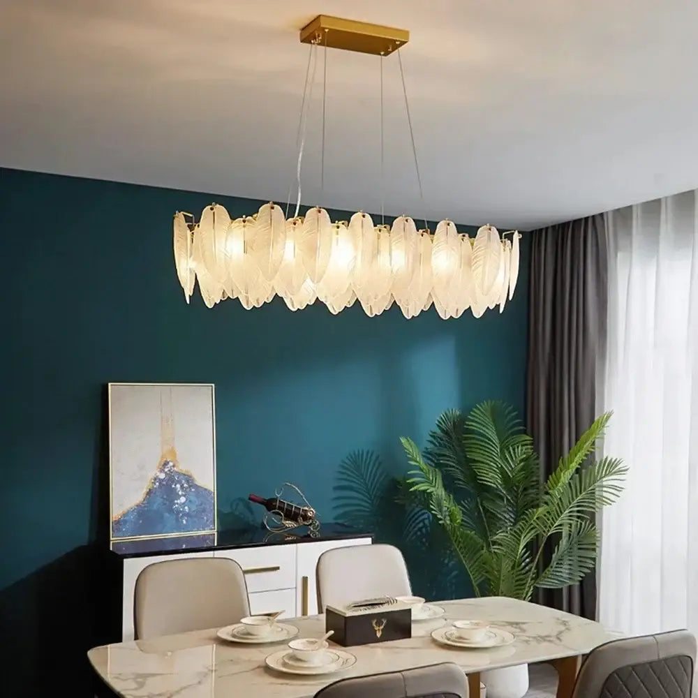 Modern gold crystal feather chandelier with translucent feather-shaped glass elements in a curved row by decorbites crystal