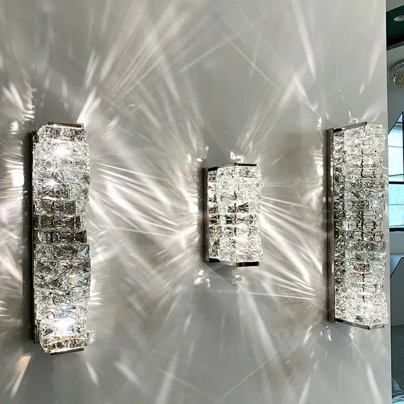 Three modern gold crystal glass wall sconces with sleek rectangular metallic frames for warm bedroom decorbites light