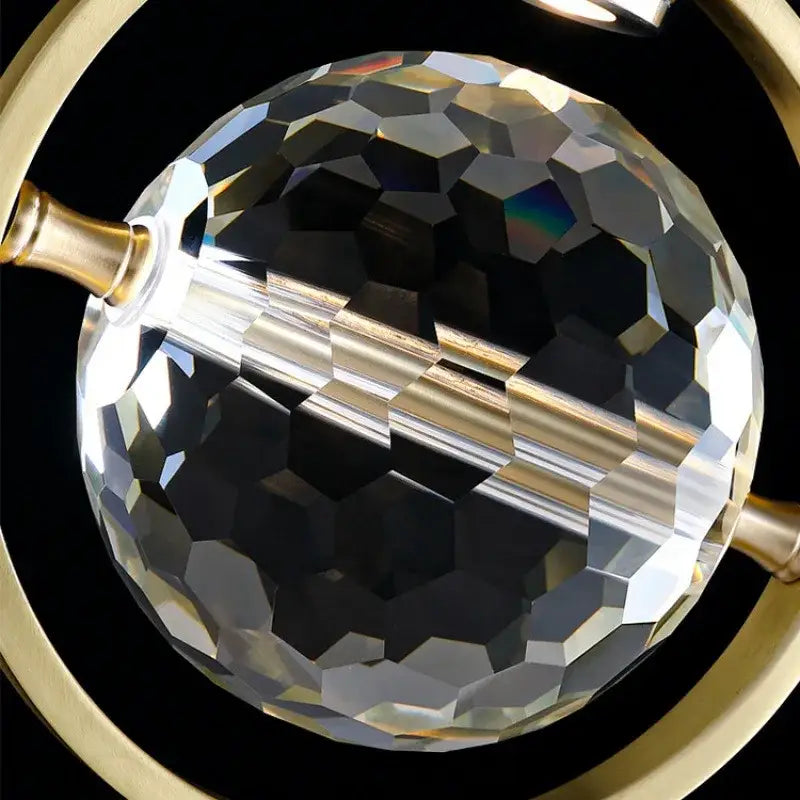 A faceted crystal globe with gold-toned metallic ring and rod in modern gold decorbites crystal led ceiling lamp