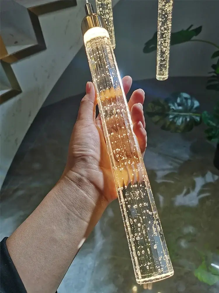 A modern gold crystal led chandelier pendant light with a cylindrical glass body filled with glowing bubbles by decorbites crystal led