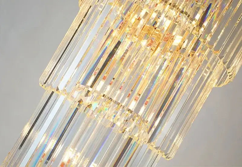 Modern gold crystal led pendant chandelier with cascading rectangular prisms refracting light in dining room decorbites crystal led