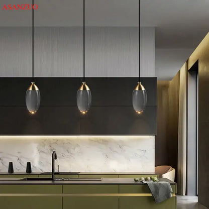 Three elegant modern gold crystal led pendant lights with glass shades hang above a kitchen island decorbites crystal led