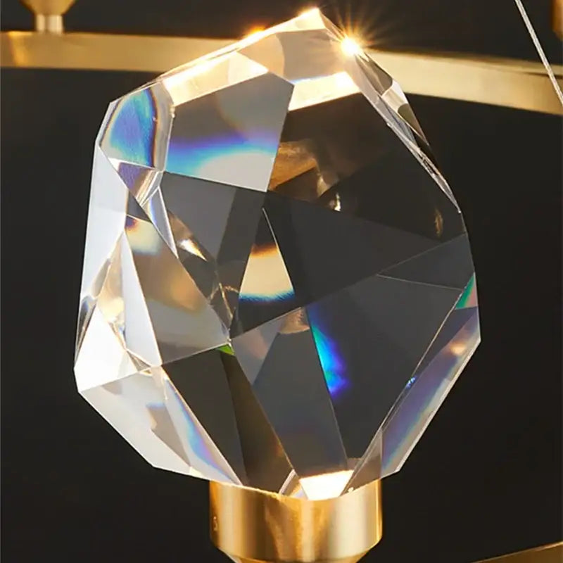 A faceted crystal led pendant light with a gold-toned metallic base for modern dining room pendant lights