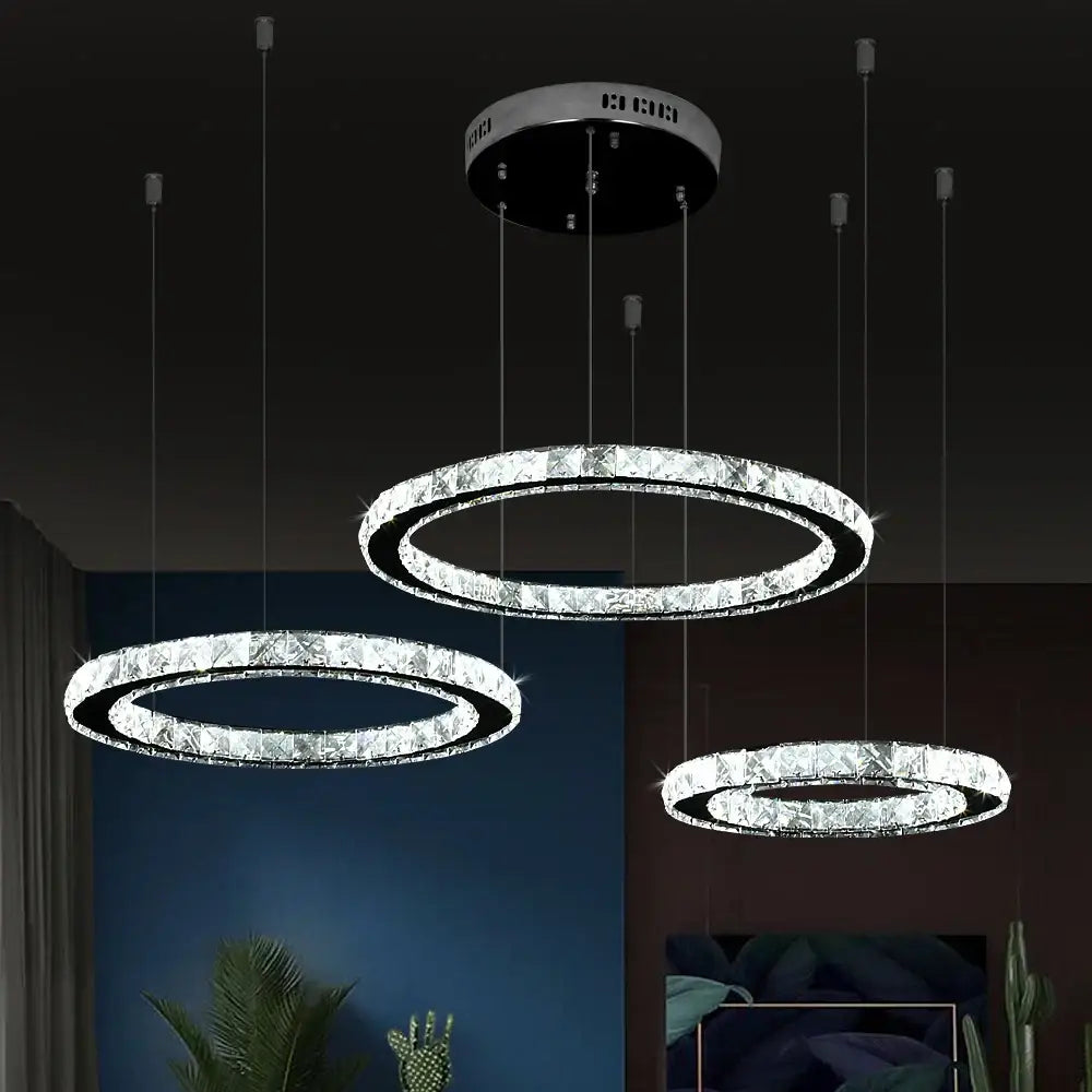 Three modern circular led ring chandeliers with sparkling crystal led decorbites rings and sleek silver fixtures for living room