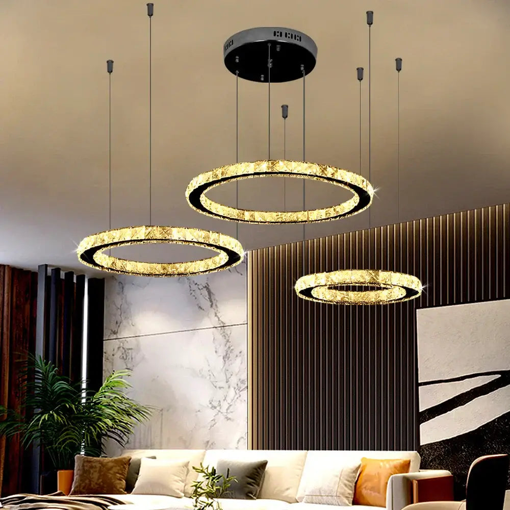 Three modern gold crystal led ring chandeliers with black fixtures hang stylishly as living room pendant lights decorbites crystal led