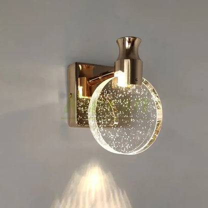 Modern gold crystal led wall lamp with a clear glass globe and embedded golden specks for elegant bedroom decorbites crystal led