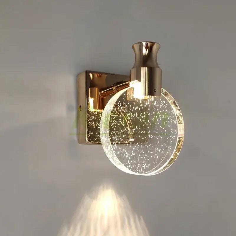 Modern gold crystal led wall lamp with a clear glass globe and embedded golden specks for elegant bedroom decorbites crystal led