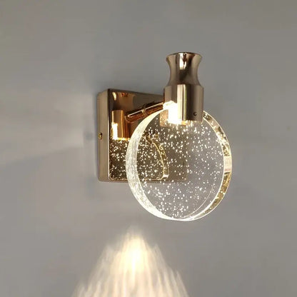 Modern gold crystal led wall lamp featuring a gold-toned sconce with a clear glass globe filled with sparkling particles