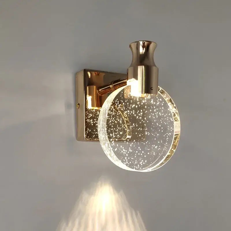 Modern gold crystal led wall lamp featuring a gold-toned sconce with a clear glass globe filled with sparkling particles