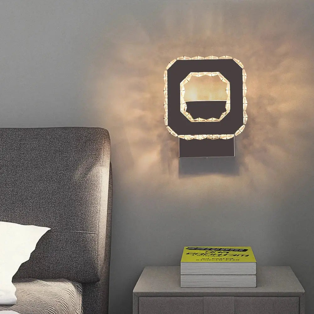 Modern black wall lamp with a geometric faceted crystal frame emitting warm light decorbites crystal led wall sconce