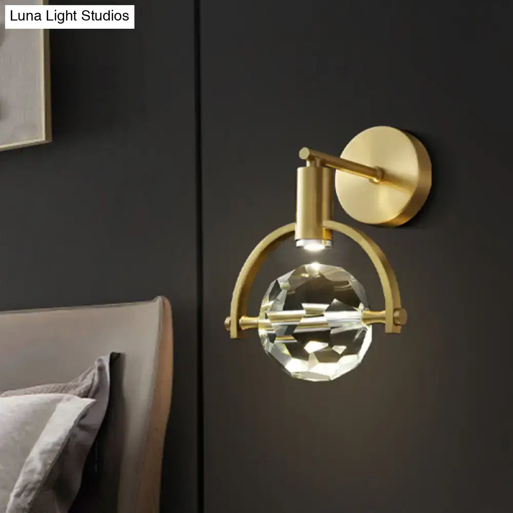 Modern gold led wall lamp featuring a faceted crystal globe on an arched brass frame with a bulb base