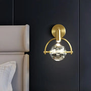 Modern gold led wall lamp featuring a faceted crystal globe suspended by an arched metal frame bulb base