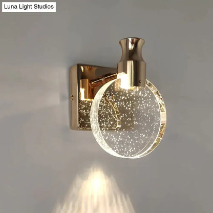 Modern gold crystal led wall lamp featuring a gold-toned wall sconce with a clear globe filled with sparkling particles